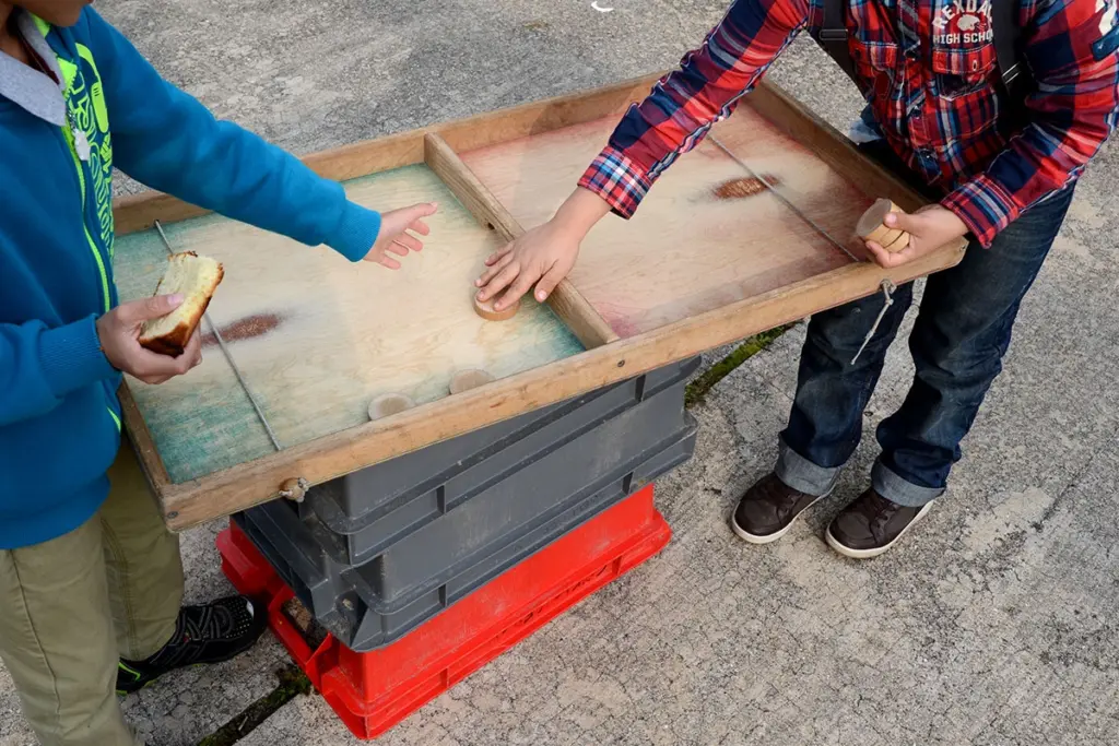 Zwei Kinder spielen Flitzpuck, man sieht ihre Gesichter nicht